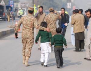 Un soldado se lleva a dos niños tras ser evacuados de la escuela. REUTERS.