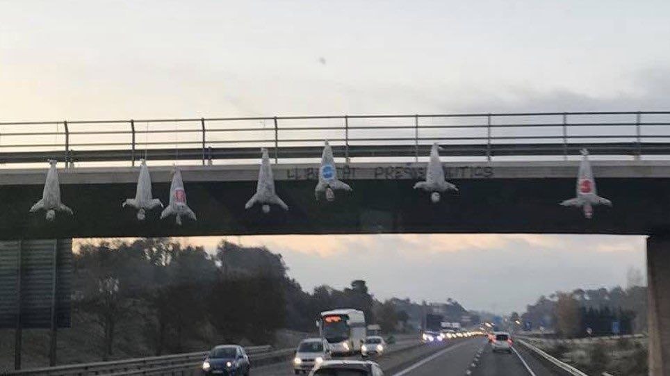 Unos desconocidos cuelgan en un puente muñecos boca abajo con logos de Cs, PSC y PP